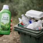 Bouteille écologique tenue devant poubelle remplie de plastique