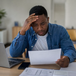 Homme préoccupé consultant un relevé devant un ordinateur