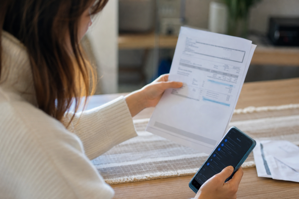 Personne tenant une facture papier et smartphone