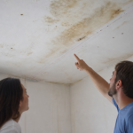 Plafond avec taches d'humidité, deux personnes pointent