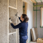 Artisan posant panneaux isolants dans ossature murale